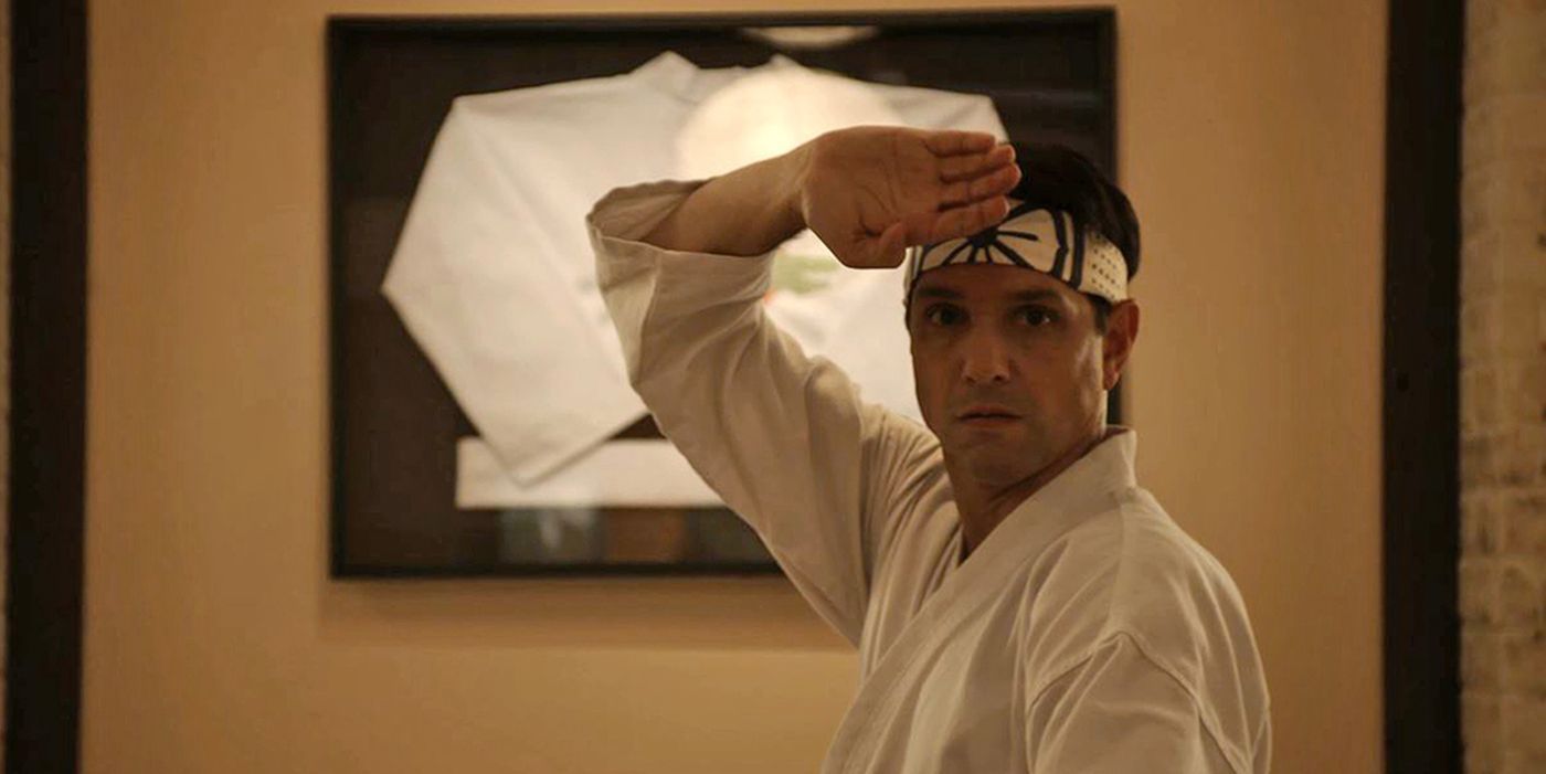 Daniel stands with a hand above his head in his dojo in Cobra Kai