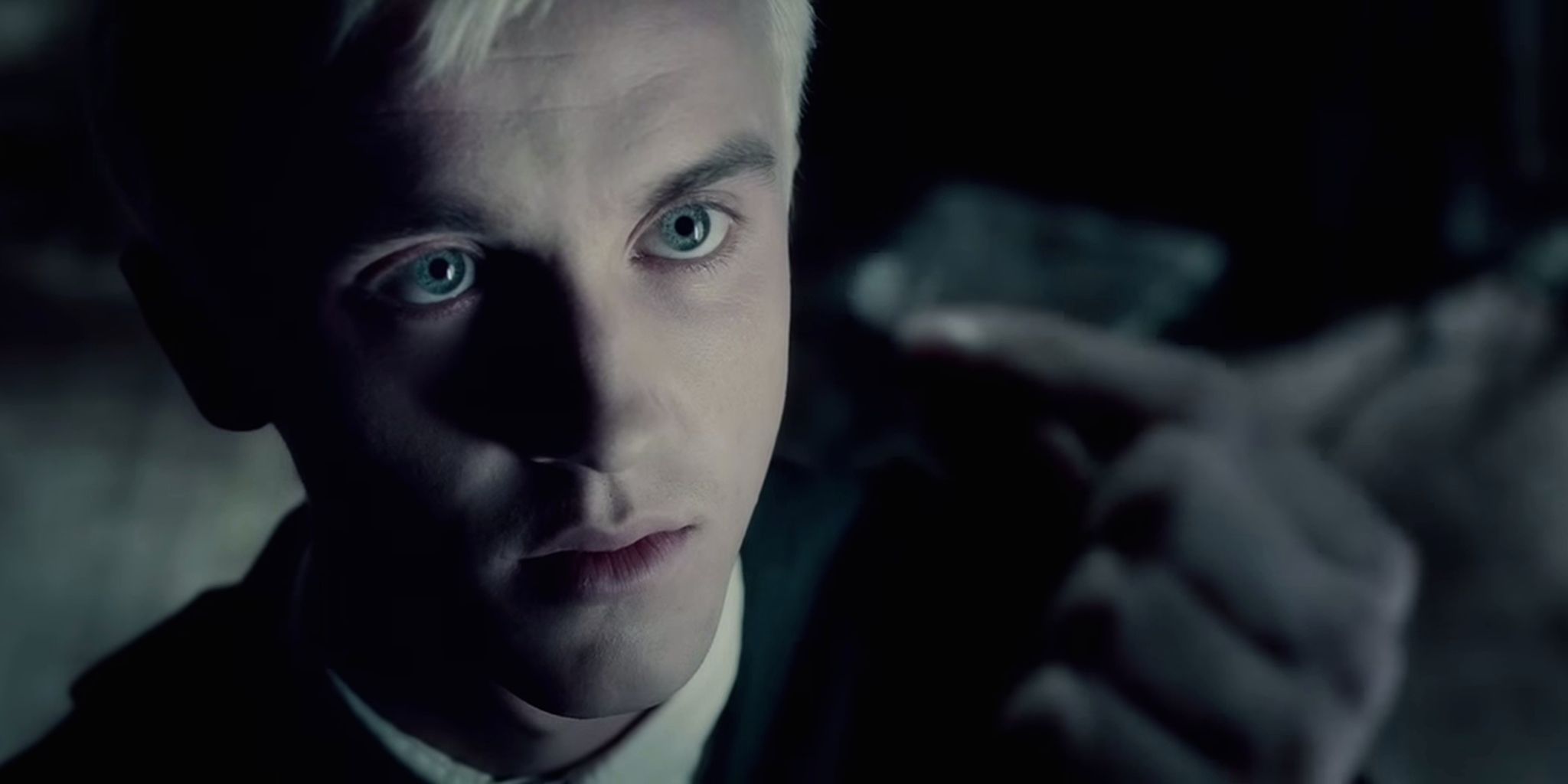 Draco Malfoy looking up at a piece of paper in his hand in Harry Potter and the Half-Blood Prince. 