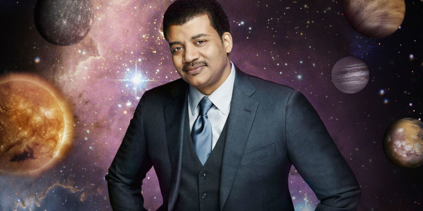Neil DeGrasse Tyson standing with planets in the background in Cosmos