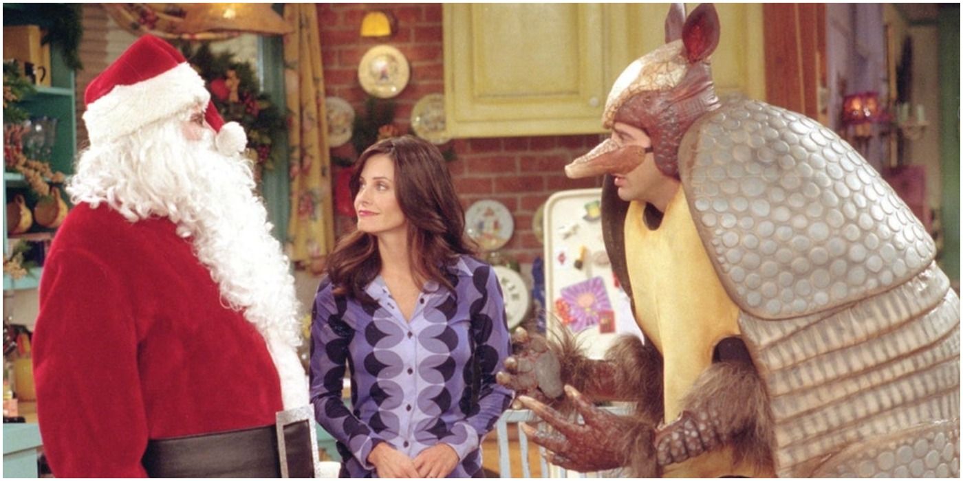Monica olha para Chandler vestido de Papai Noel e Ross vestido como o tatu do feriado em seu apartamento em Friends.