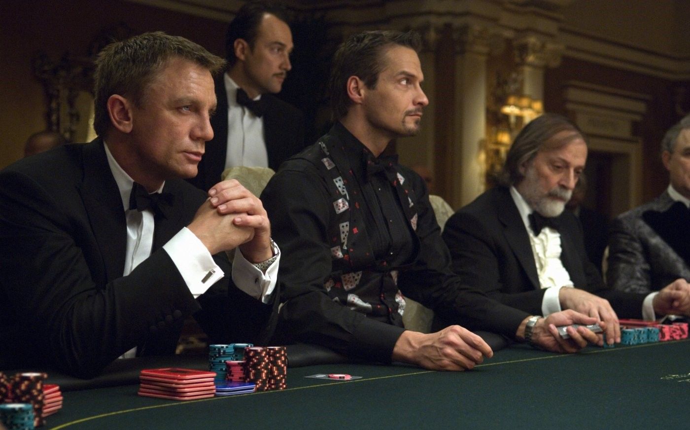 Daniel Craig As James Bond Sitting At Card Table With Others