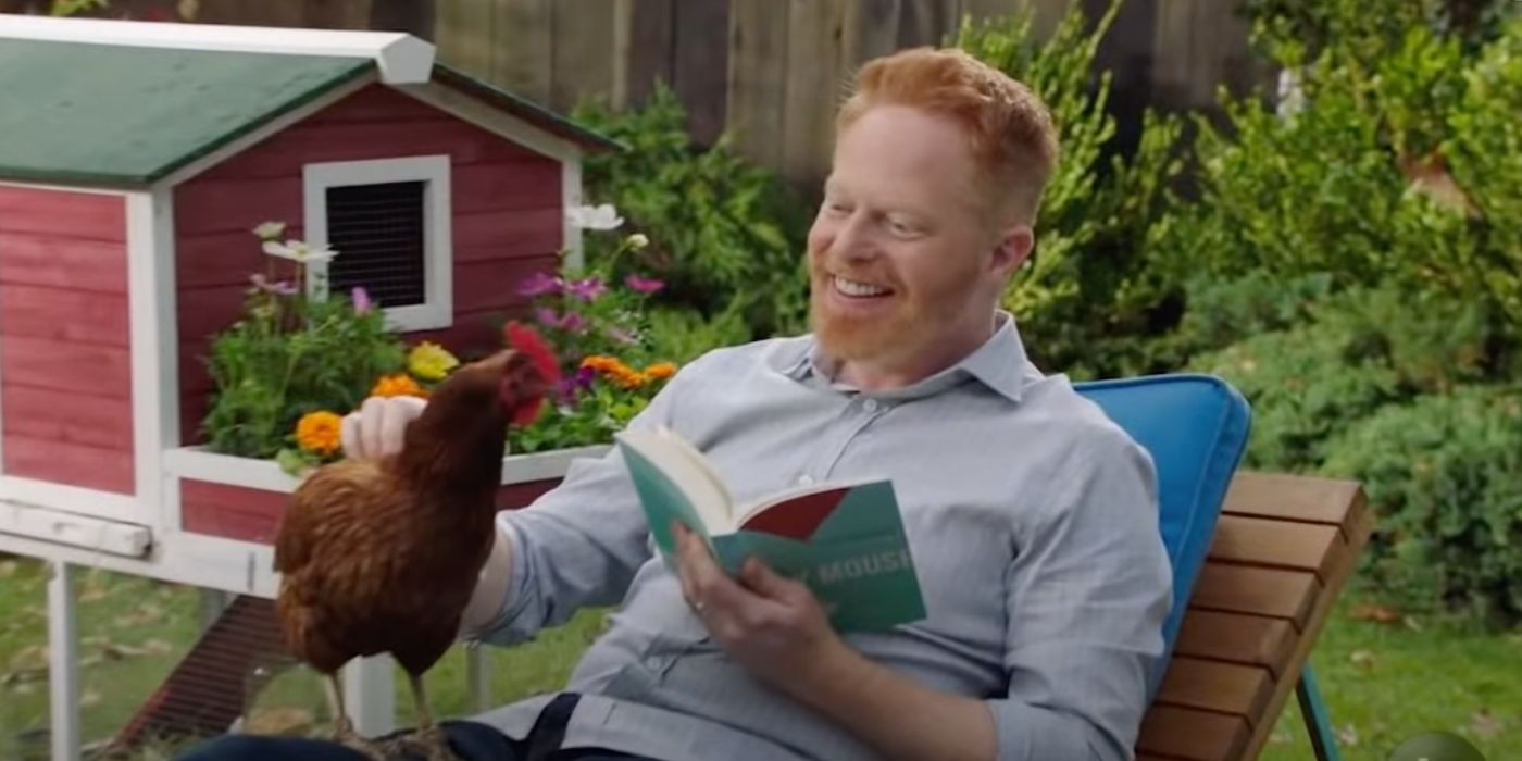 Mitch smiling with a chicken while reading on Modern Family