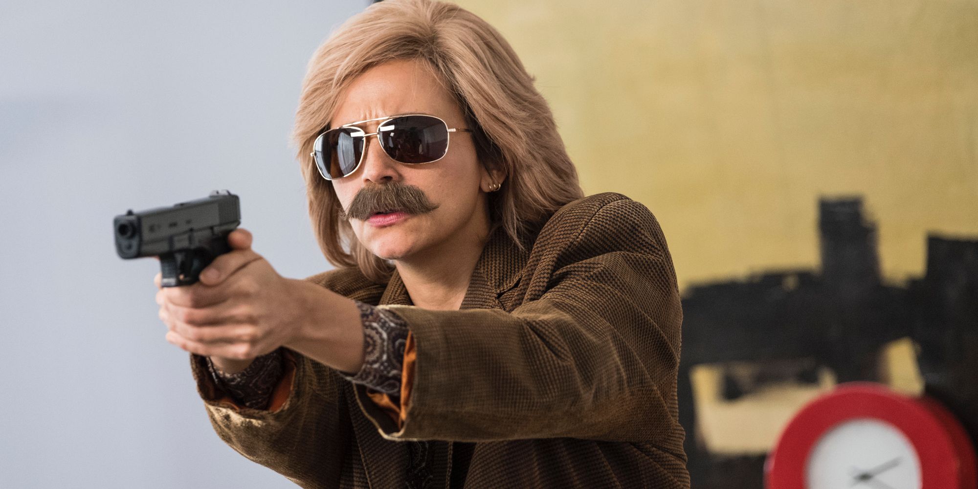 Rashida Jones with a wig and fake mustache pointing a gun in Angie Tribeca 