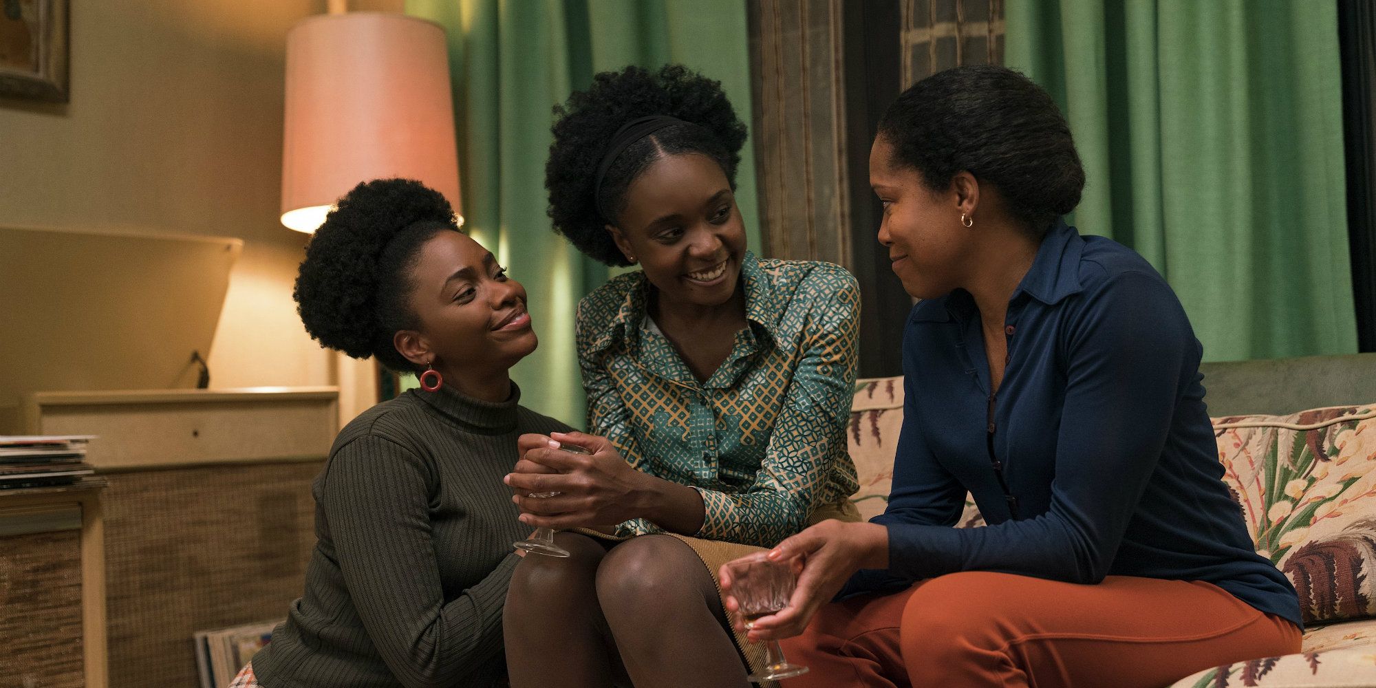Tish, her sister, and Sharon on the couch smiling in If Beale Street Could Talk