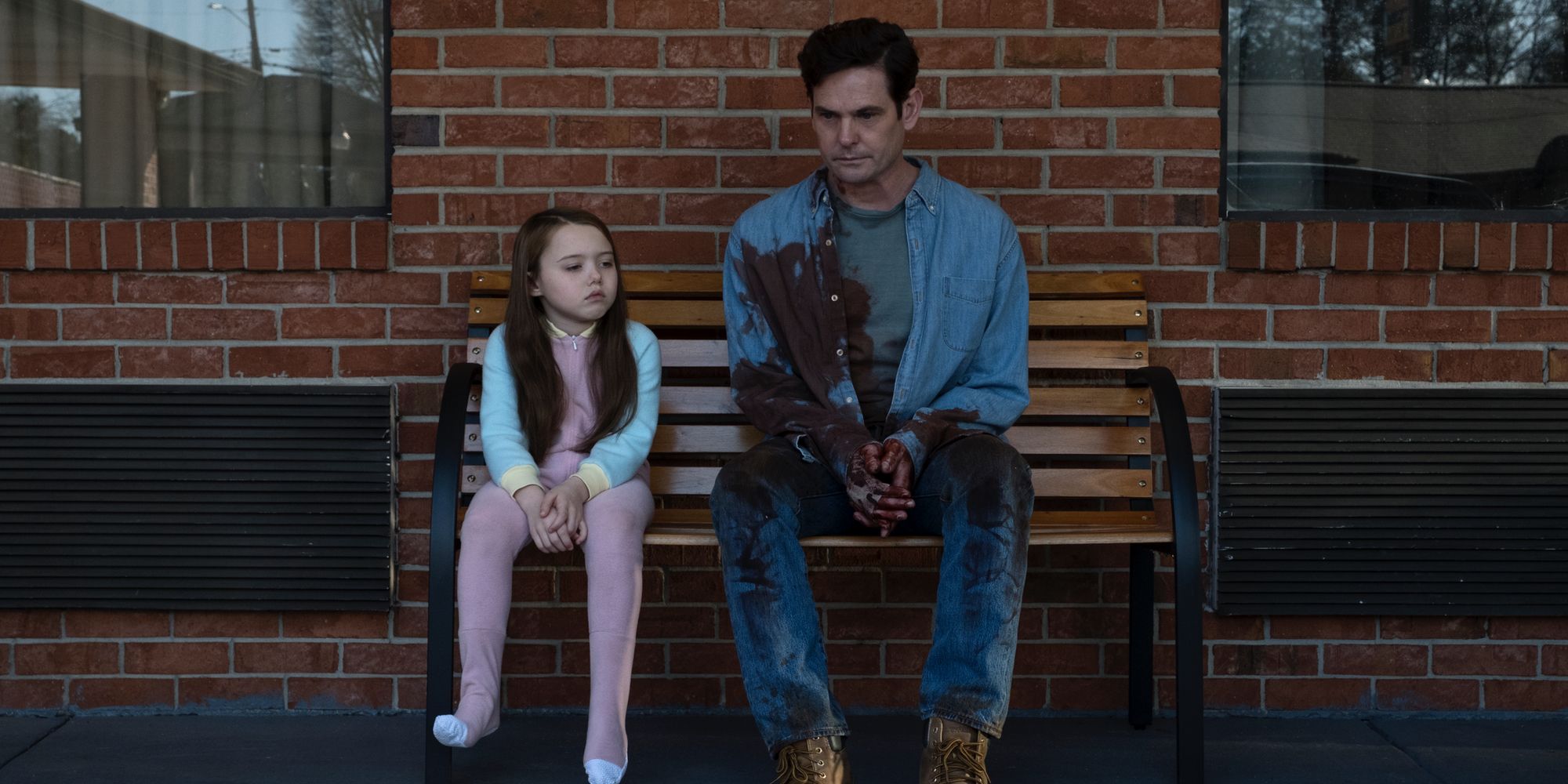 A bloody Hugh Crain sits on a bench with his daughter Nell Crain