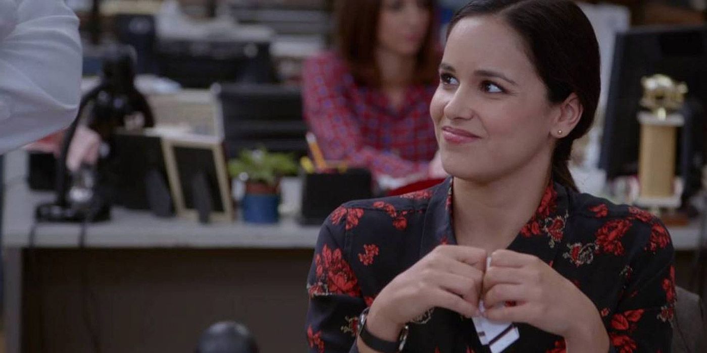 Amy smiling at her desk in Brooklyn Nine-Nine