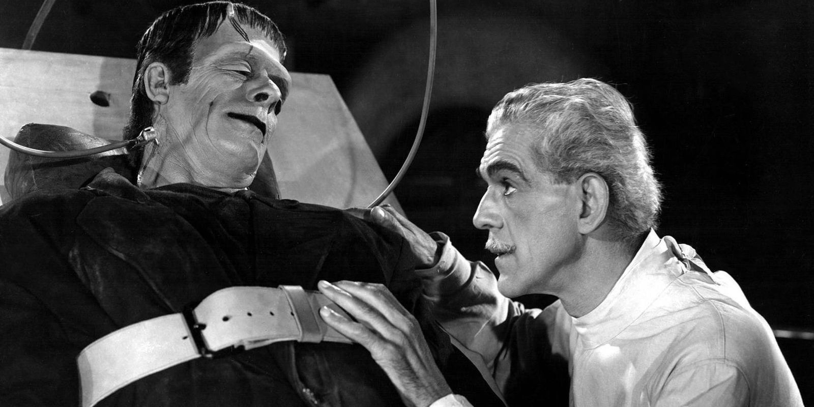 Frankenstein's monster strapped to a bed and being watched by Doctor Frankenstein