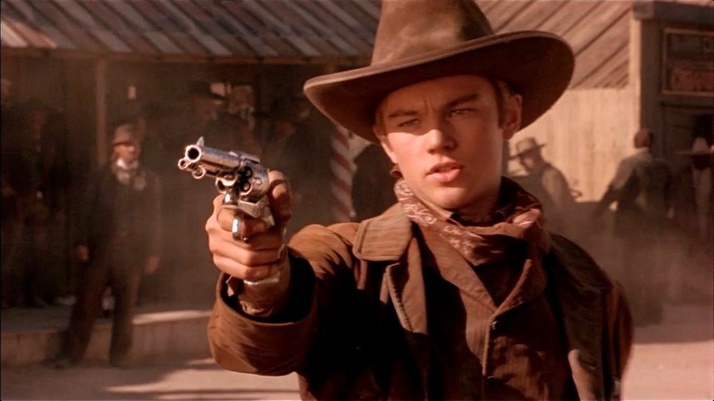 Leonardo Dicaprio wearing cowboy hat and shooting a gun in a duel in Quick and the Dead