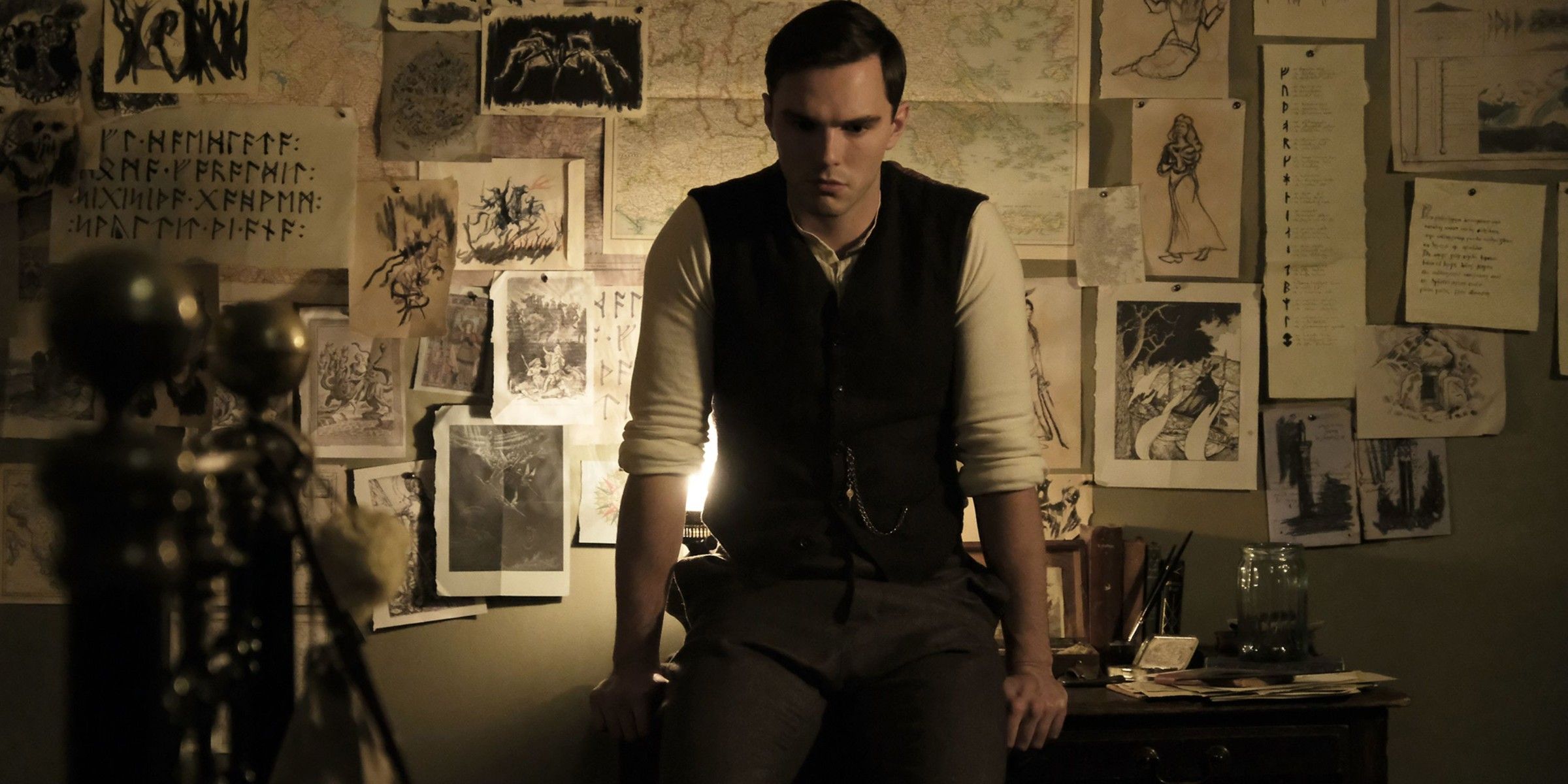 Nicholas Hoult in front of a wall of sketches and notes in Tolkien movie