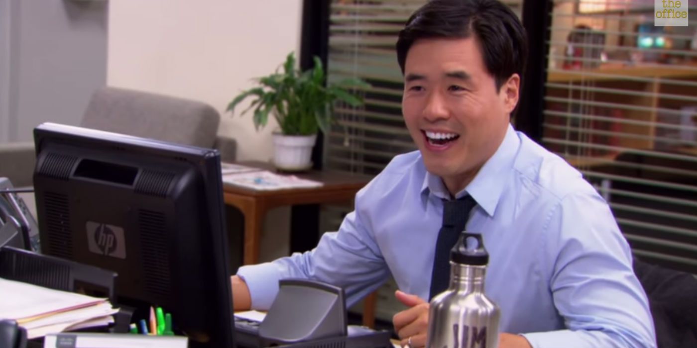 Randall Park in The Office smiling at his desk
