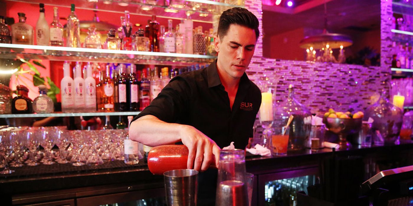 Tom Sandoval in a black shirt pouring drinks behind a bar