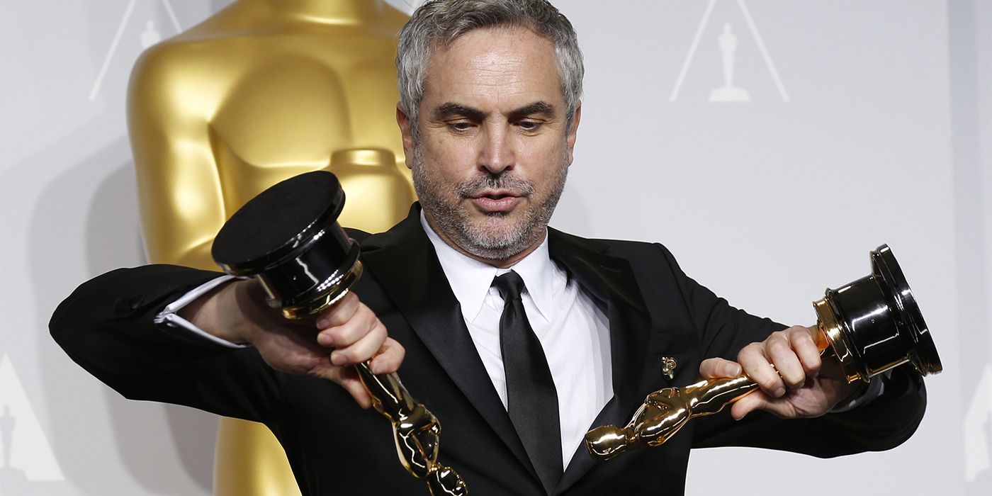 Alfonso Cuaron holding two Oscars backstage