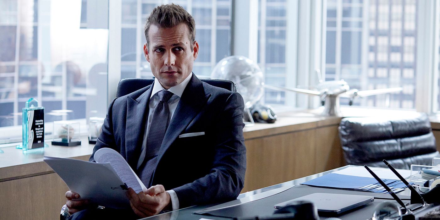 Suits Harvey Specter sitting at his desk with a file in hand