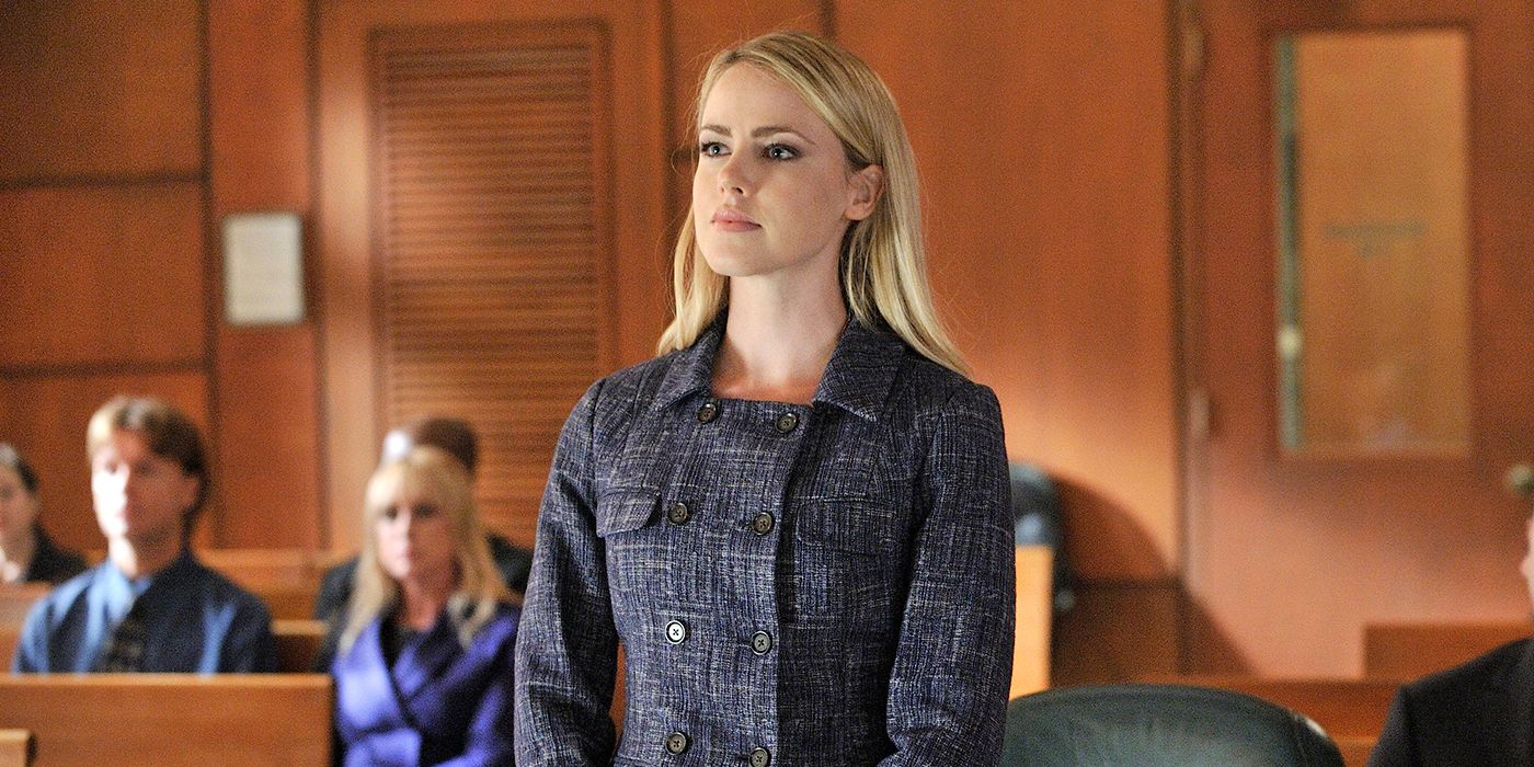 Katrina wears a dark gray dress and looks on in a courtroom in Suits 