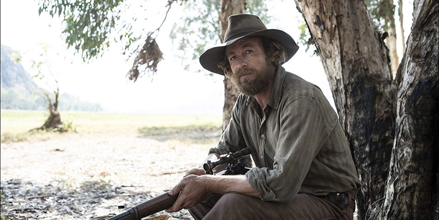 Simon Baker holding a shotgun and wearing a hat in High Ground