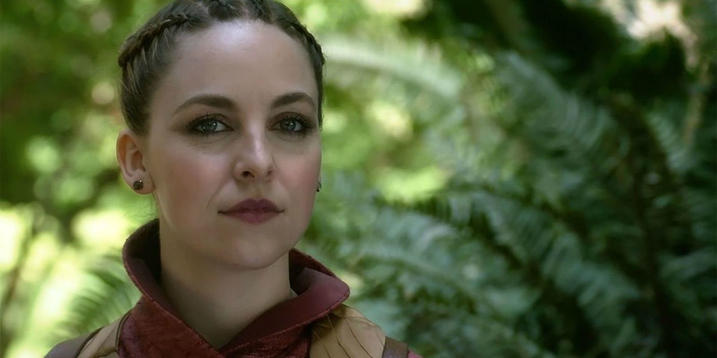 Fen smiles while standing in a wooded area in The Magicians.