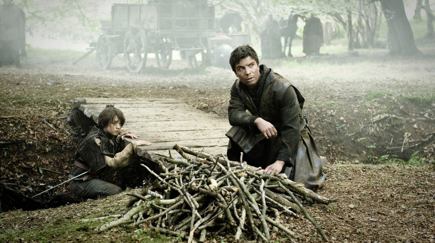 Gendry and Arya crouched by a small bridge.