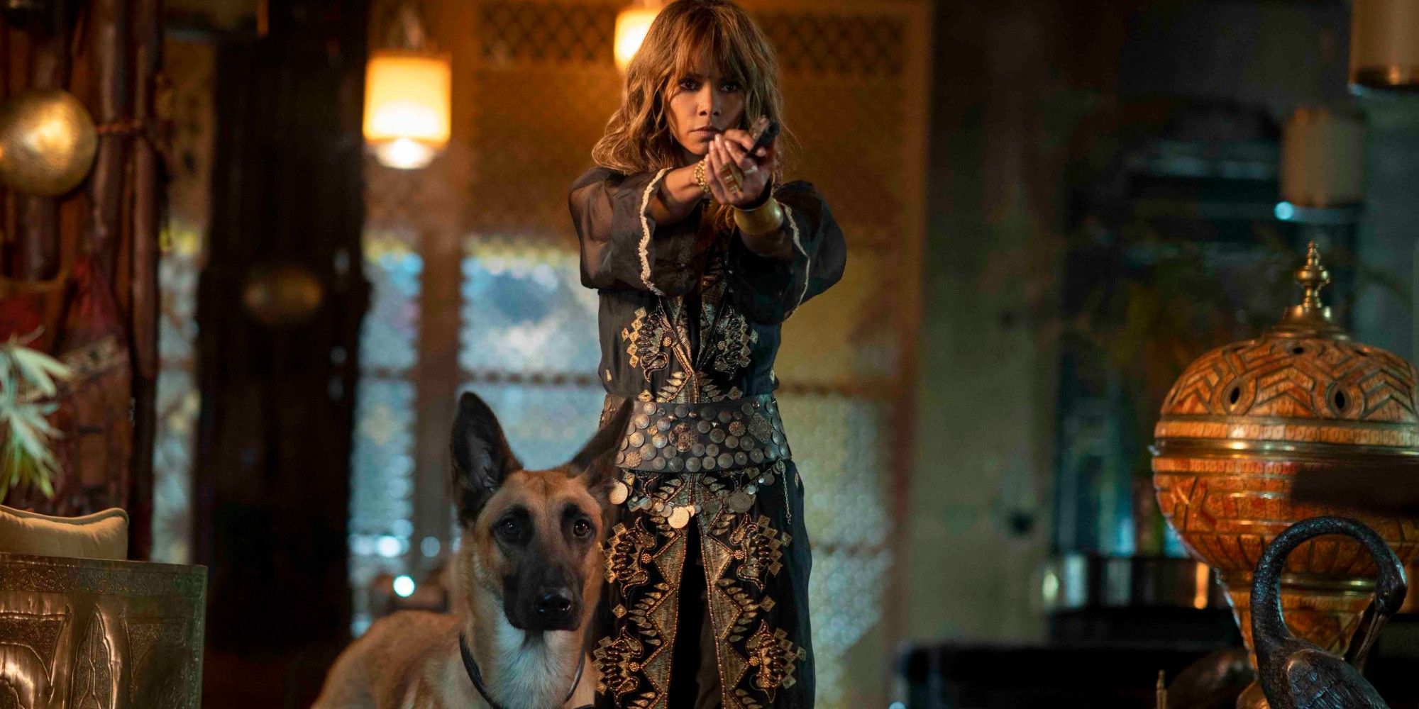 Halle Berry aiming a gun while standing with her dog in John Wick 3