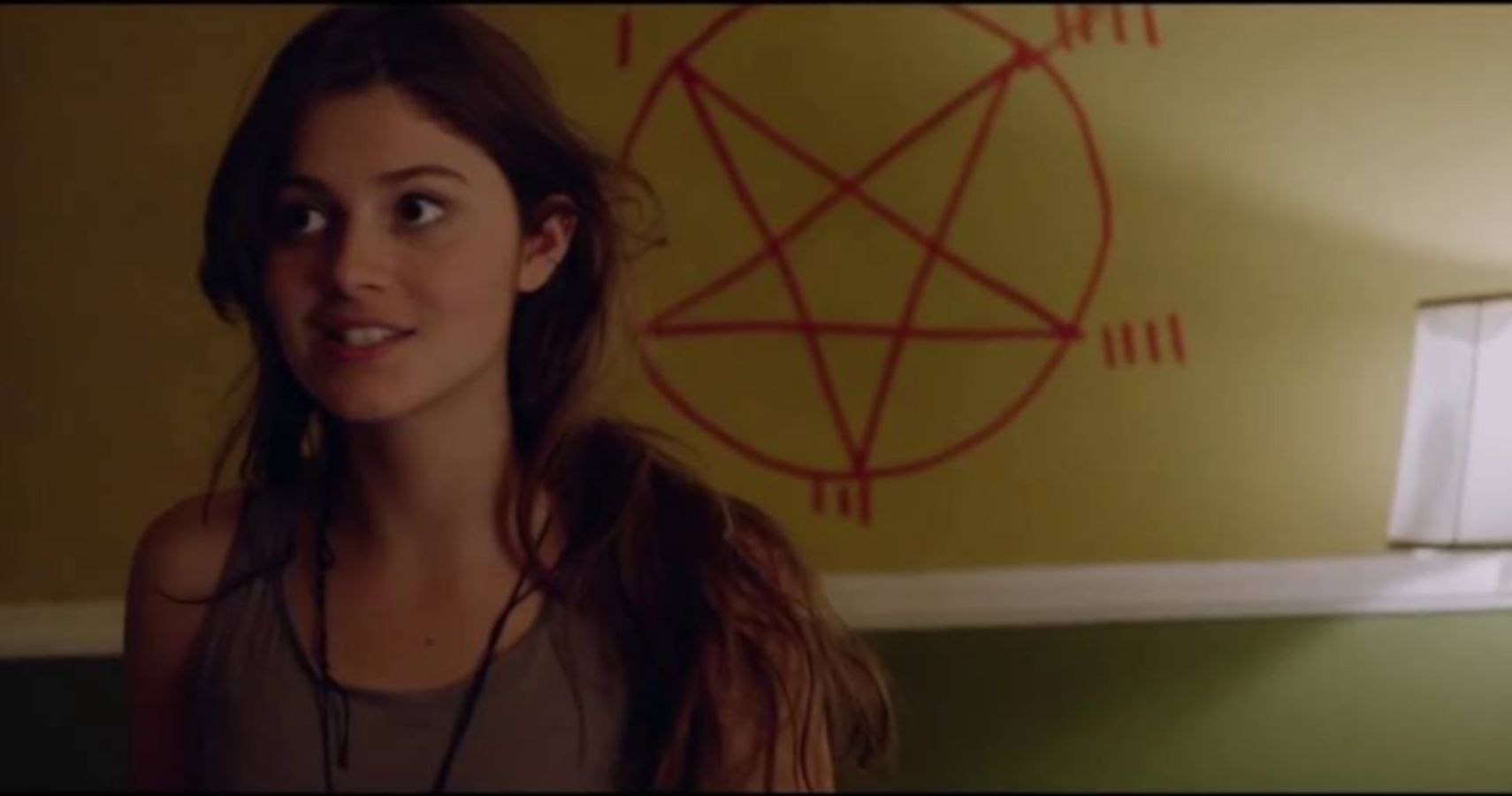 Actor standing in front of a pentagram on the wall in Satanic