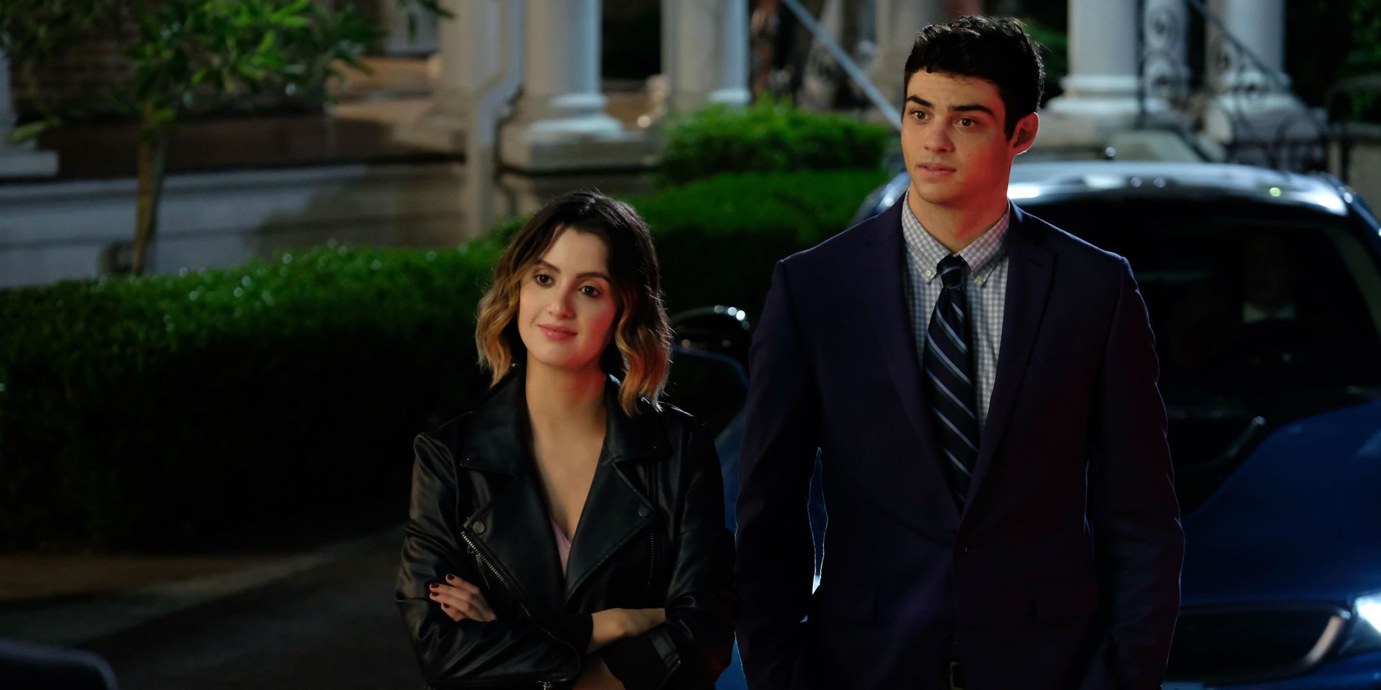 Laura Marano and Noah Centineo standing next to one another with amused expressions in The Perfect Date