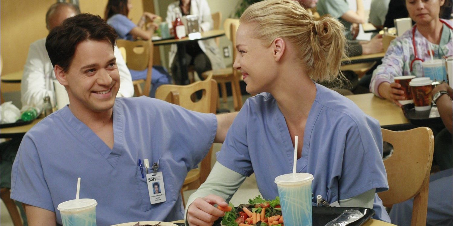 Geroge and Izzie smiling at each other in the hospital cafeteria in Grey's Anatomy
