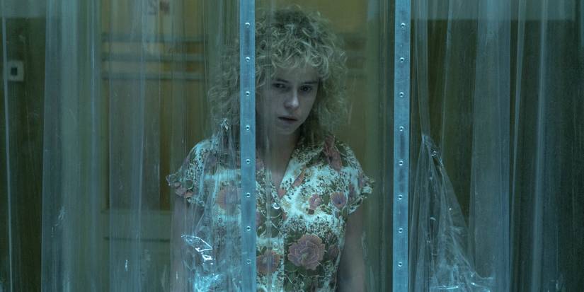 Jessie Buckley peering through a plastic curtain in Chernobyl