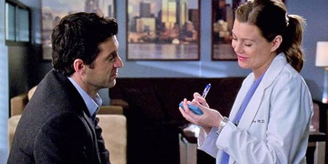 Derek standing with Meredith who is writing on a post-it note during their wedding on Grey's Anatomy