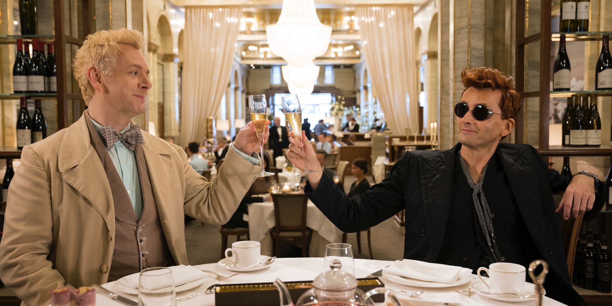 Michael Sheen e David Tennant em Good Omens Amazon segurando sua taça de vinho