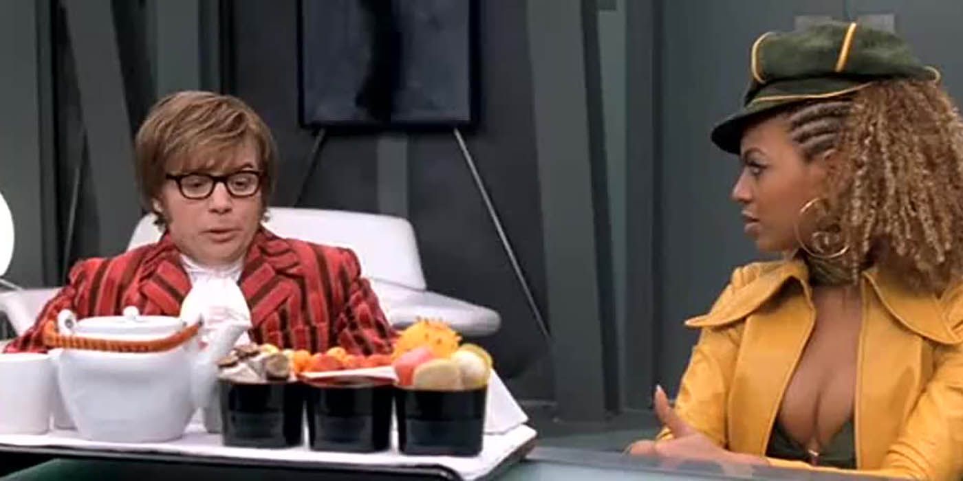 Austin Powers sentado en una mesa con Foxy Cleopatra en una escena de Austin Powers en Goldmember.