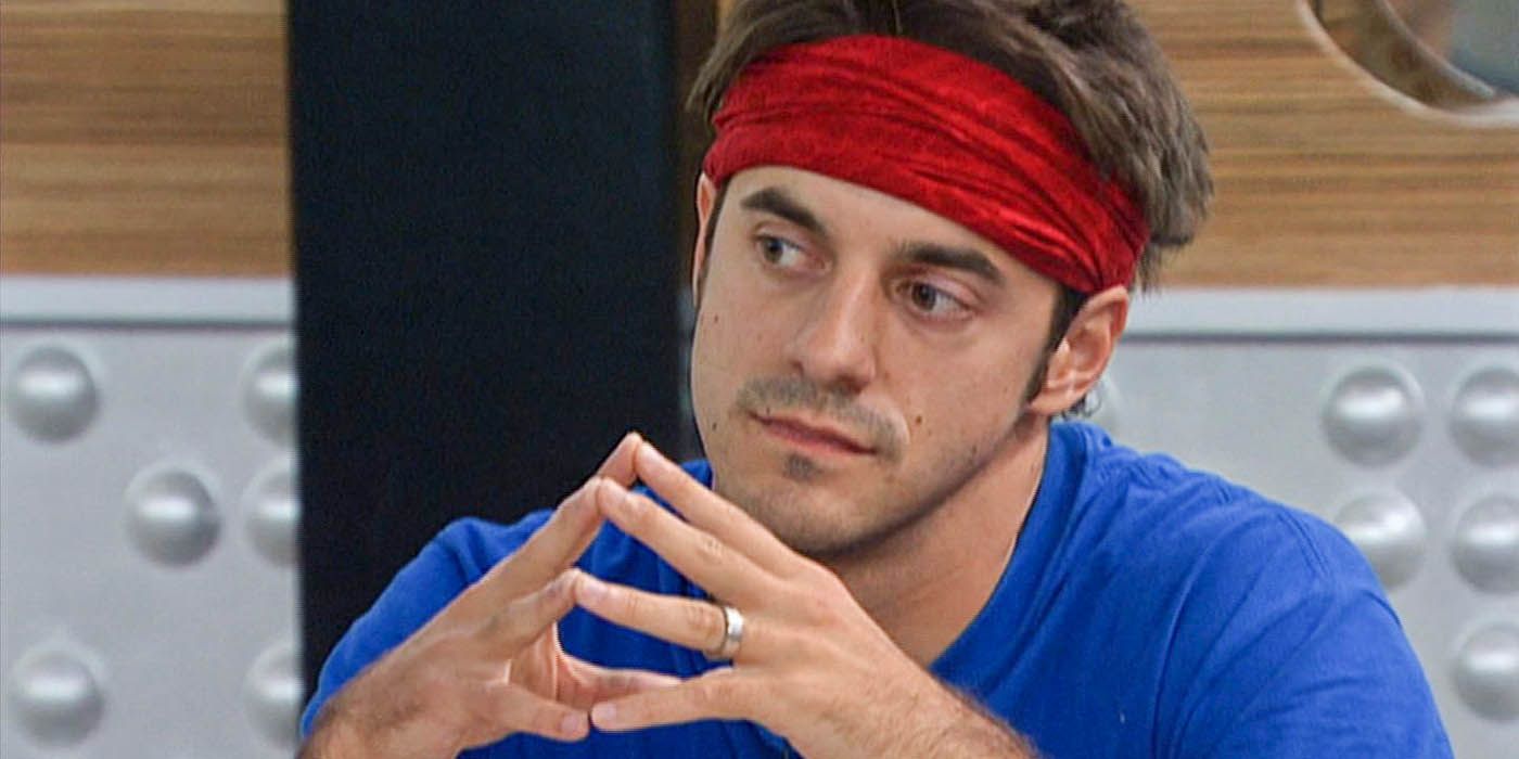 Dan Gheesling from Big Brother sitting down with a red headband and blue shirt, fingers tented together.