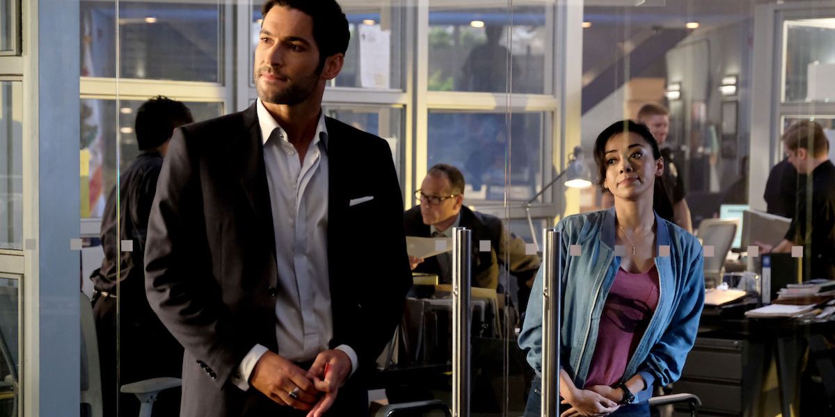 Lucifer and Ella stand on either side of a glass door at the precinct in Netflix's Lucifer series