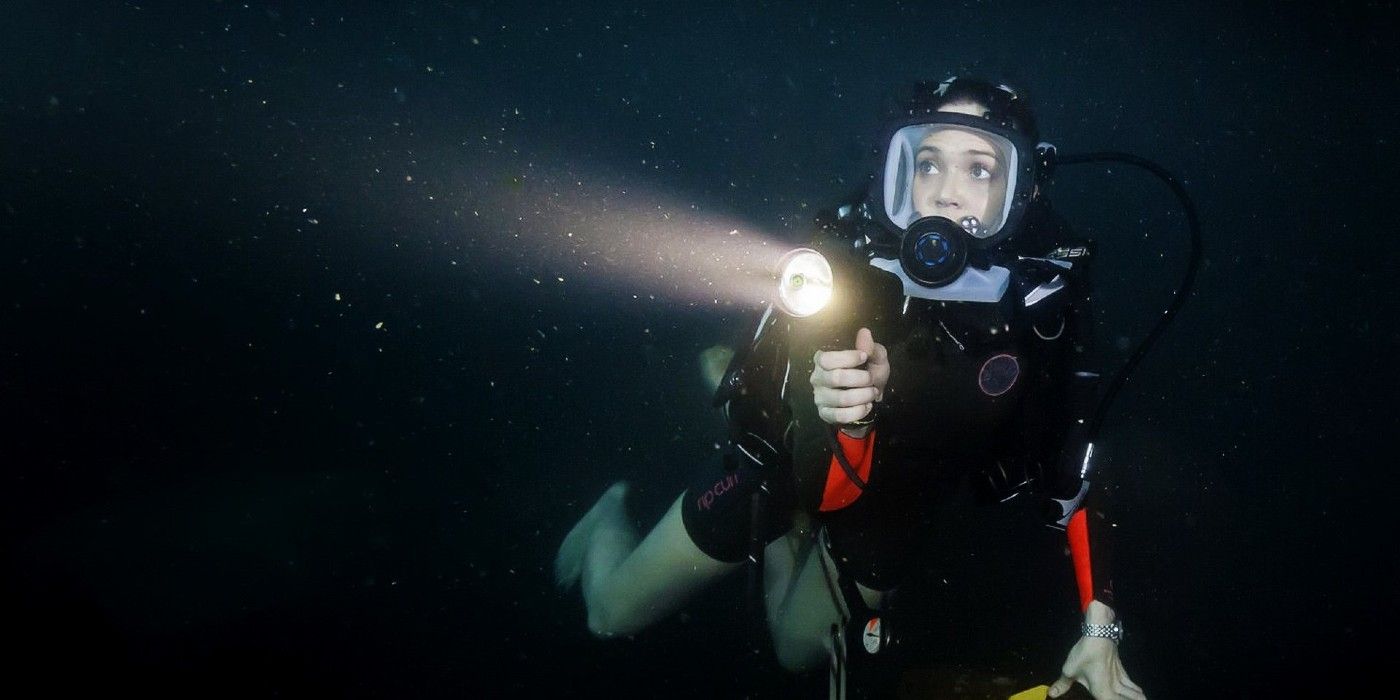 A scuba diver uses a flashlight underwater in 47 meters down