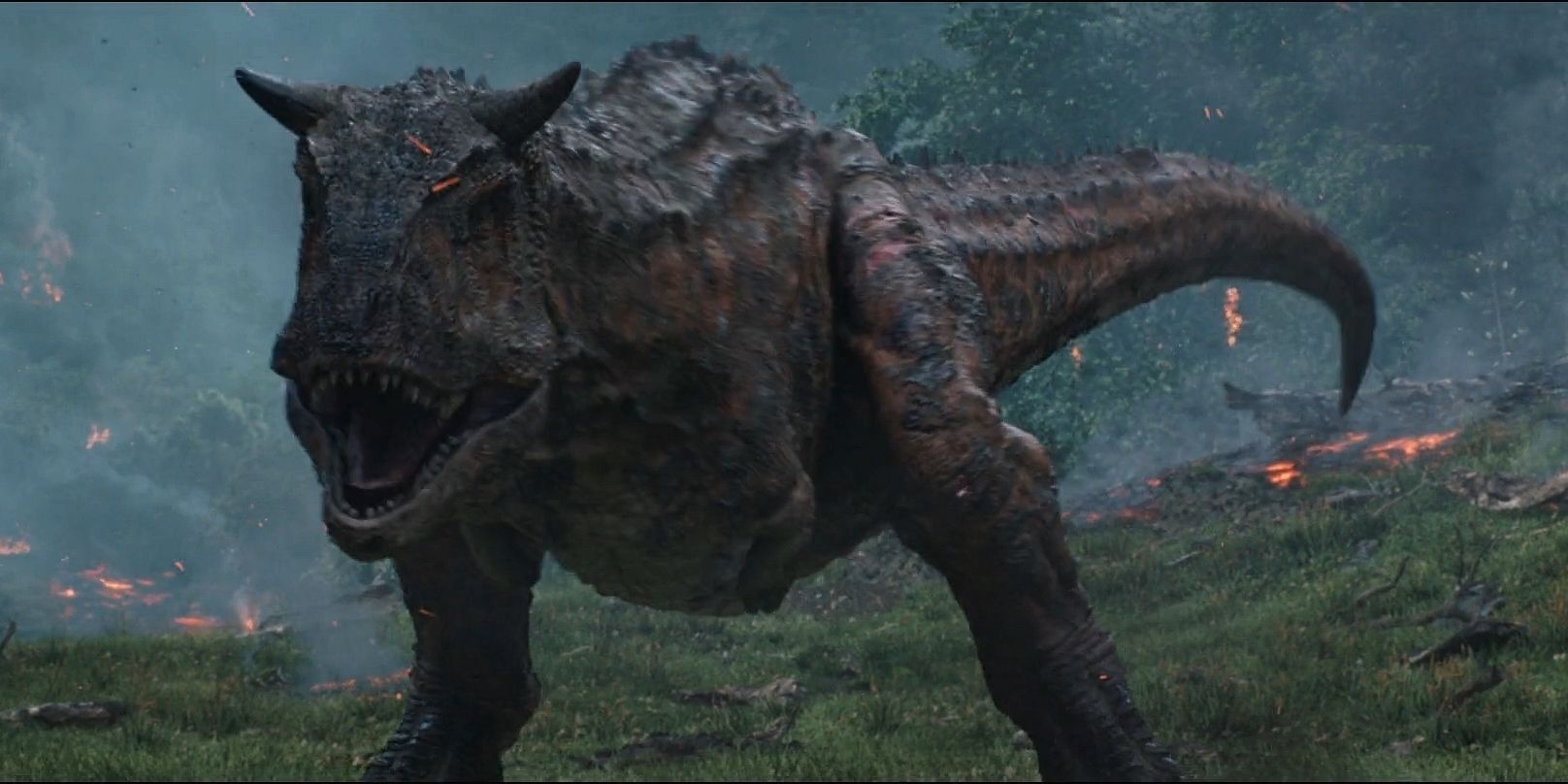 A Carnotaurus prepares to attack with the exploding volcano behind it on Isla Nublar in Jurassic World Fallen Kingdom