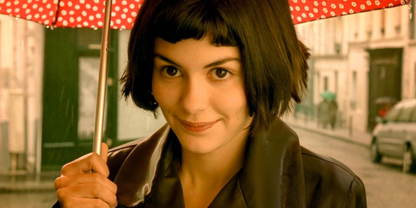 Amelie smiling under an umbrella