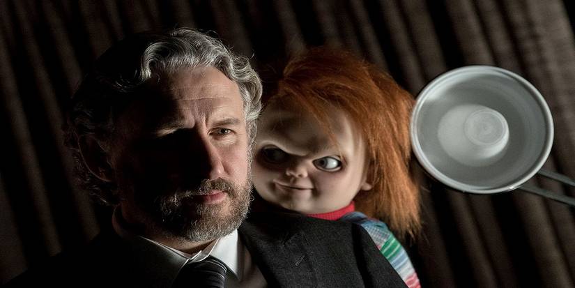 Chucky leaning over Dr. Foley's shoulder in Cult of Chucky