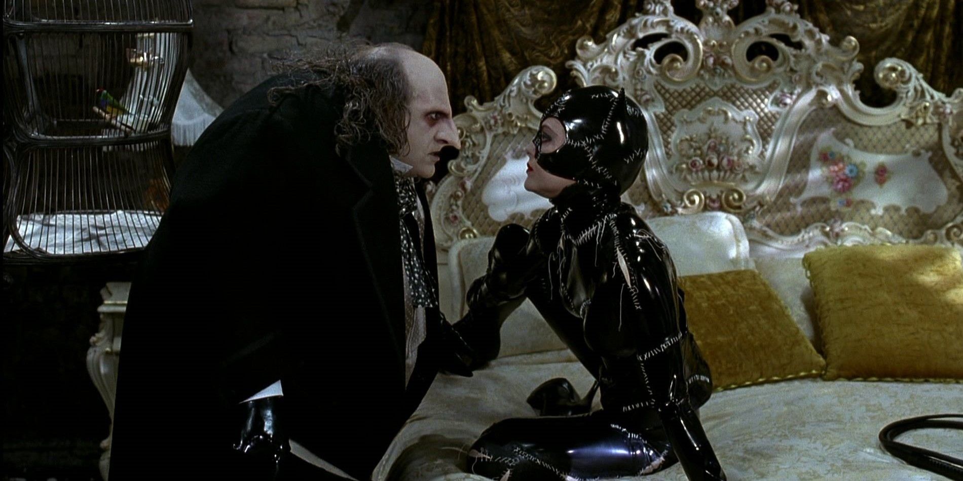 Danny DeVito as Oswald Cobblepot Penguin and Michelle Pfeiffer as Selina Kyle Catwoman sit on a bed in Batman Returns