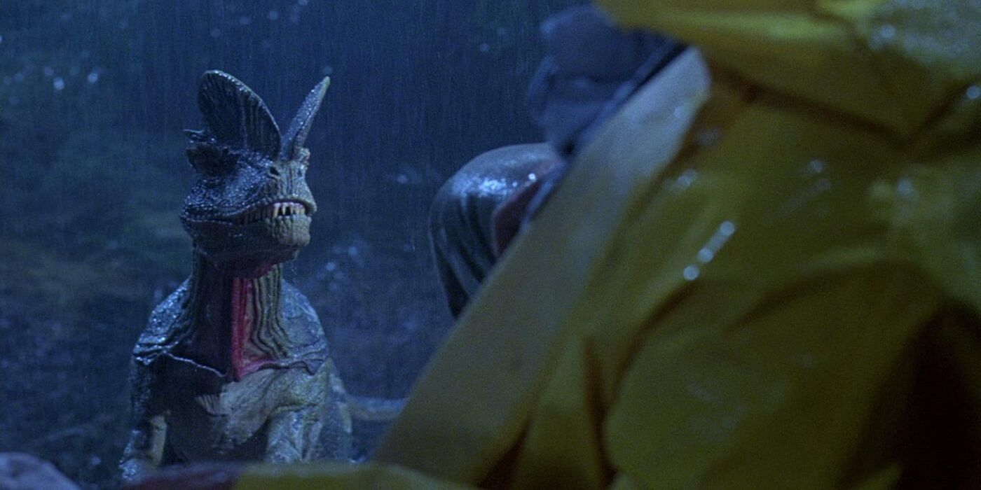 Um Dilophosaurus olha para Dennis Nedry no chão em Jurassic Park