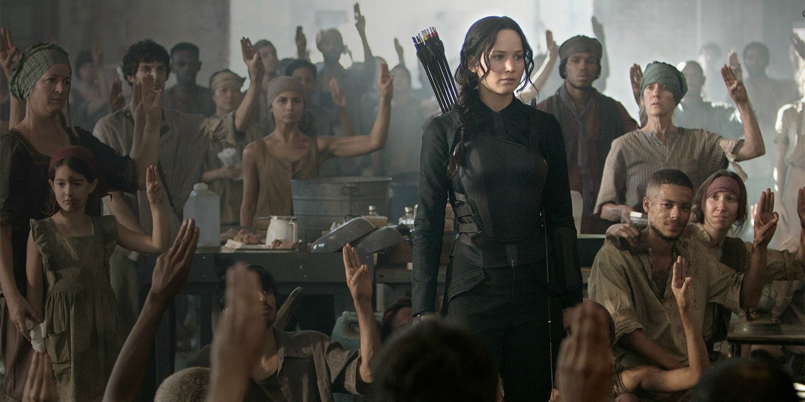 Katniss in the Hunger Games District 8 Hospital surrounded by people giving the three fingered salute.