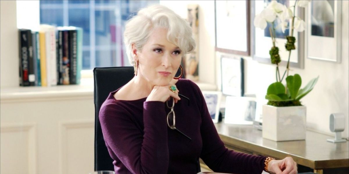 Miranda sits behind her desk and watches Andy during their first meeting