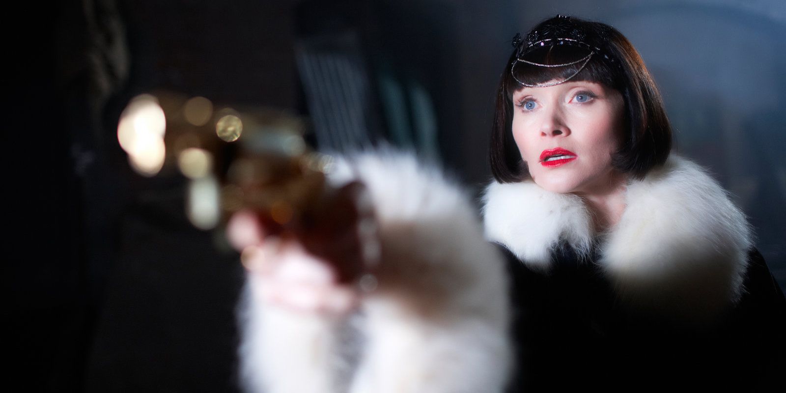Phryne Fisher pointing a gun at someone. 