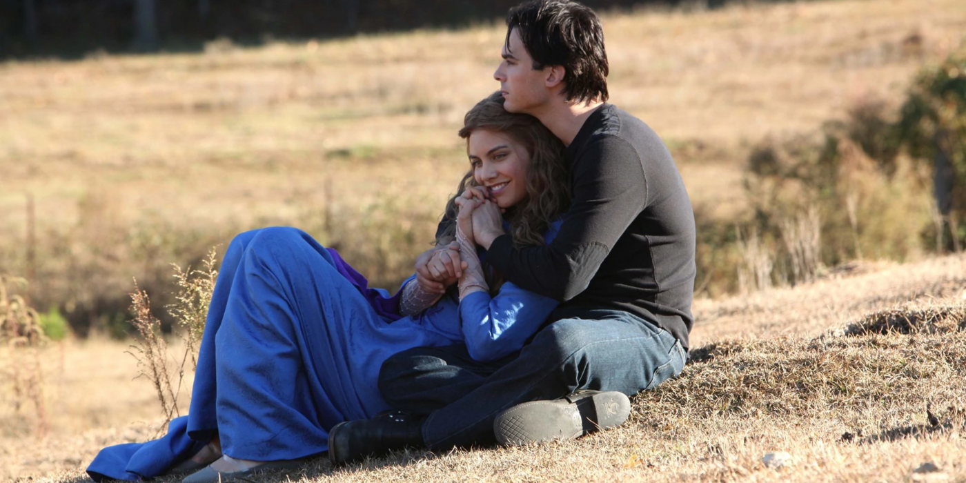 Damon embracing Rose while sitting in a field in The Vampire Diaries