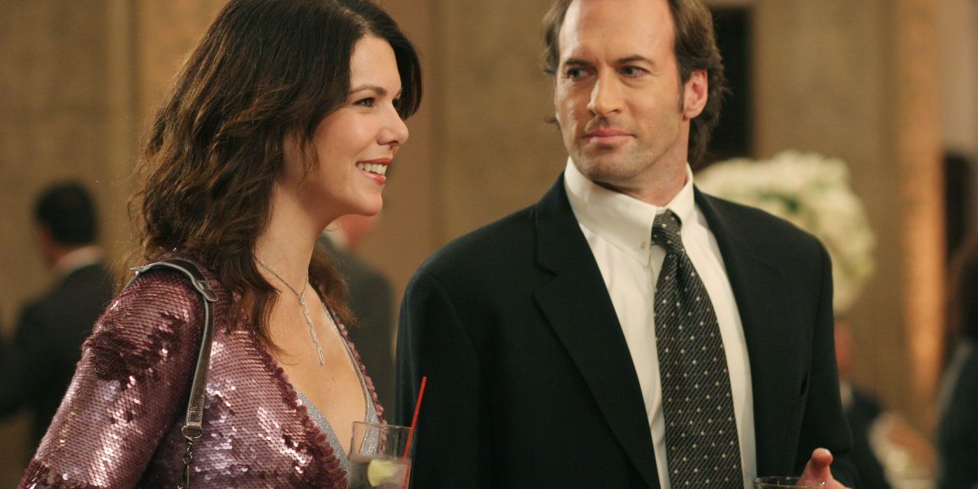 Lorelai and Luke standing together in formal clothing at a party on Gilmore Girls