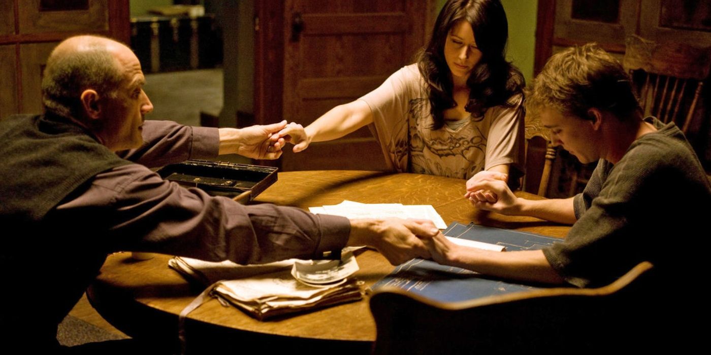 Three people hold hands around the table in The Haunting in Connecticut