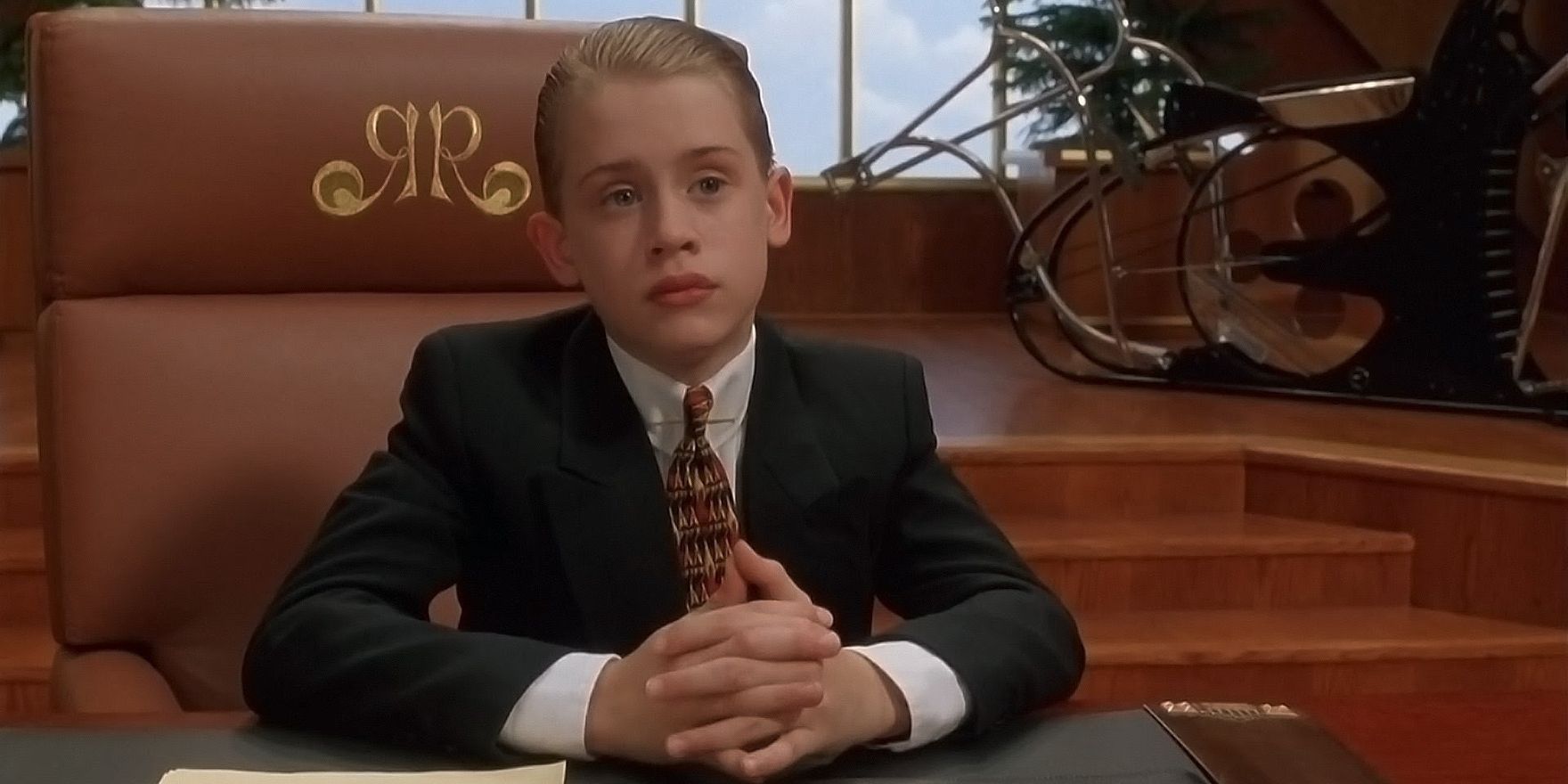 Richie Rich wearing a suit and sitting behind his desk