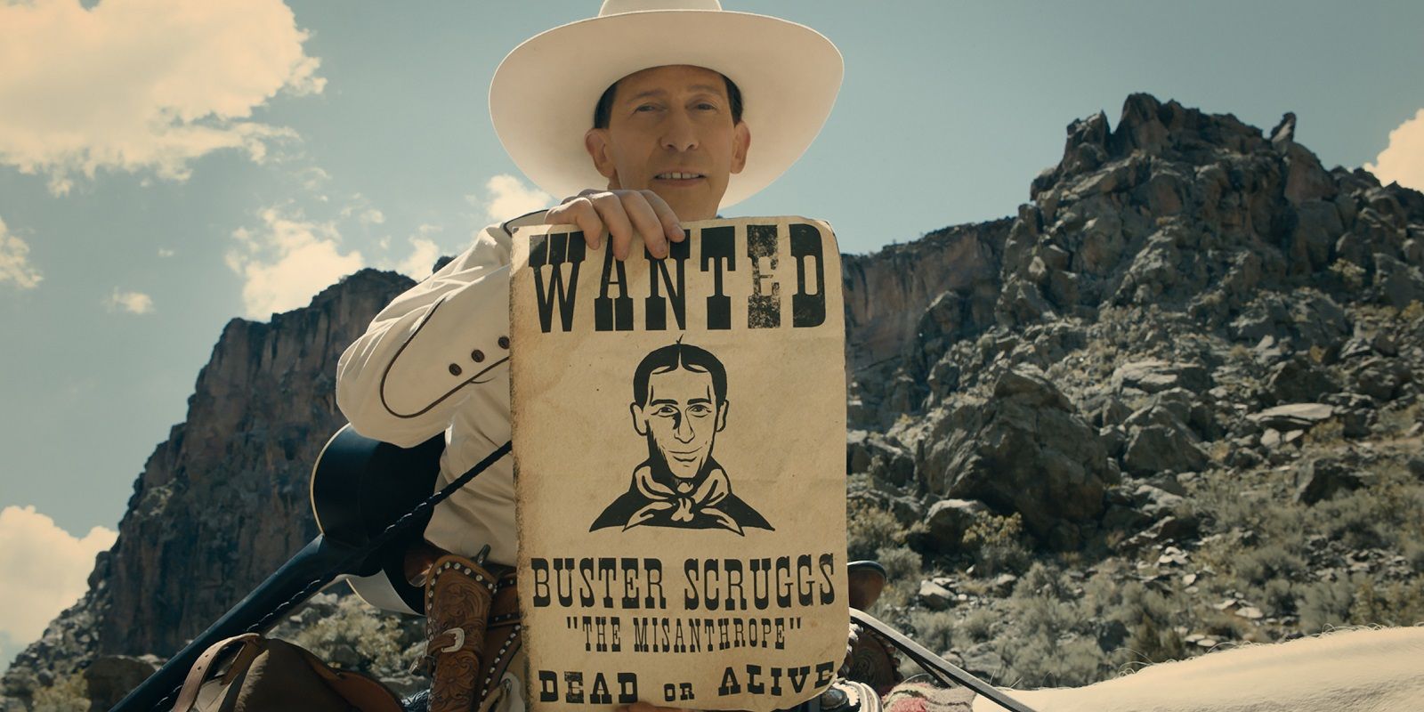 Buster Scruggs holding a wanted poster of himself