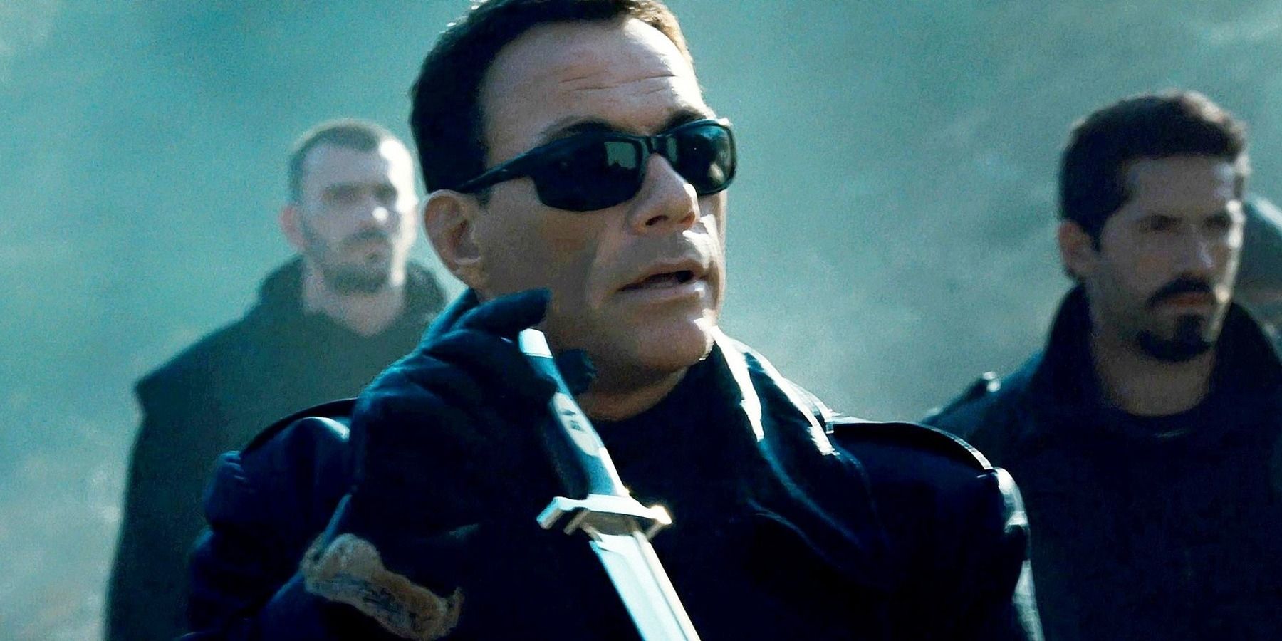 Jean-Claude Van Damme wearing sunglasses and holding a knife in The Expendables 2
