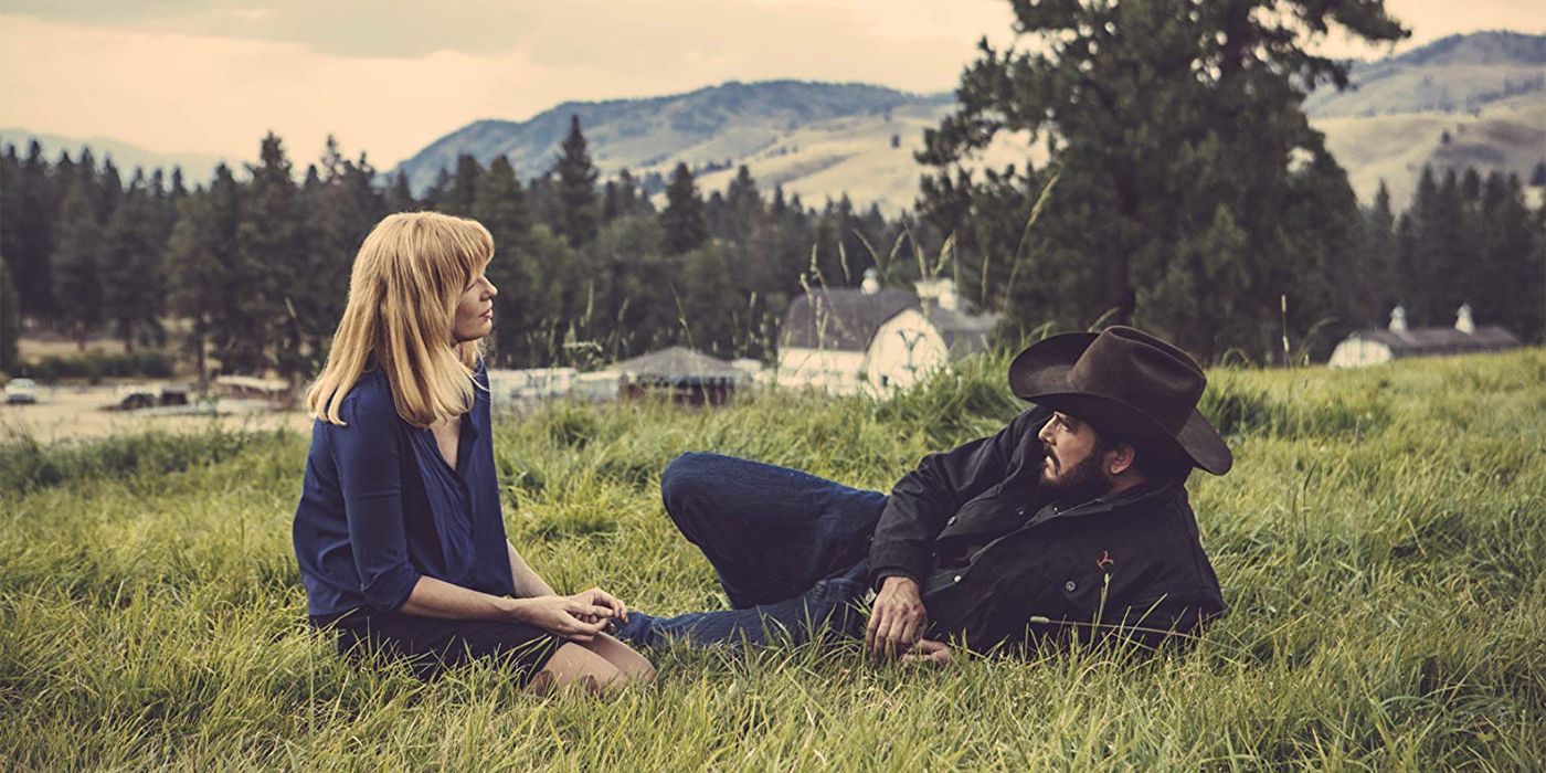 Cole Hauser and Kelly Reilly in Yellowstone sitting on the grass