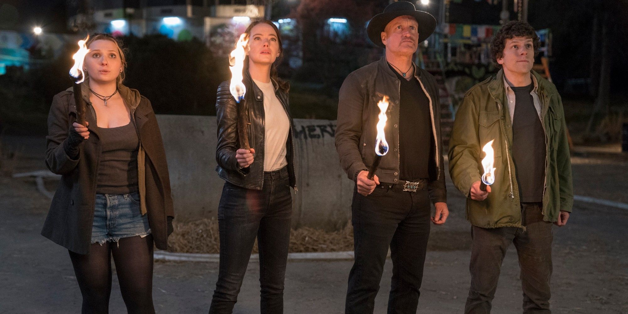 Abigail Breslin, Emma Stone, Woody Harrelson, and Jesse Eisenberg hold fire torches in Zombieland Double Tap