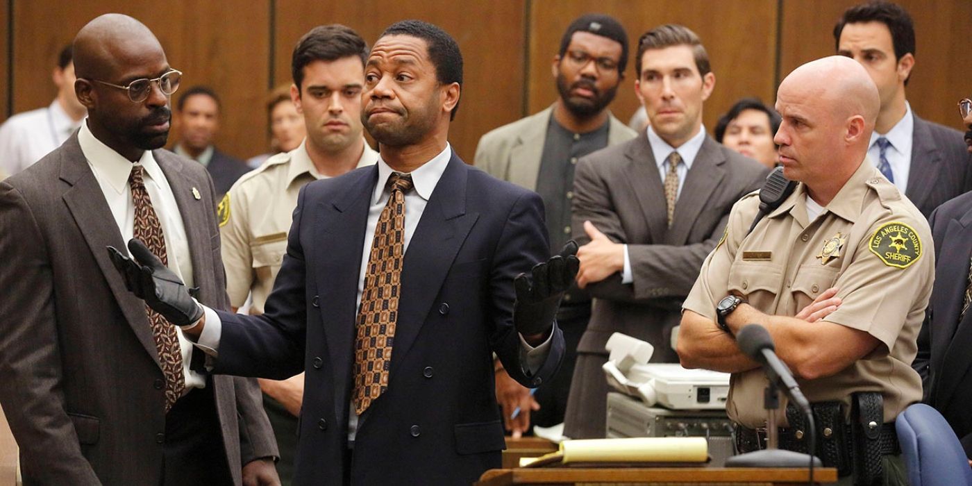 OJ Simpson holds his gloved hands up in a courtroom as everyone looks on in American Crime Story