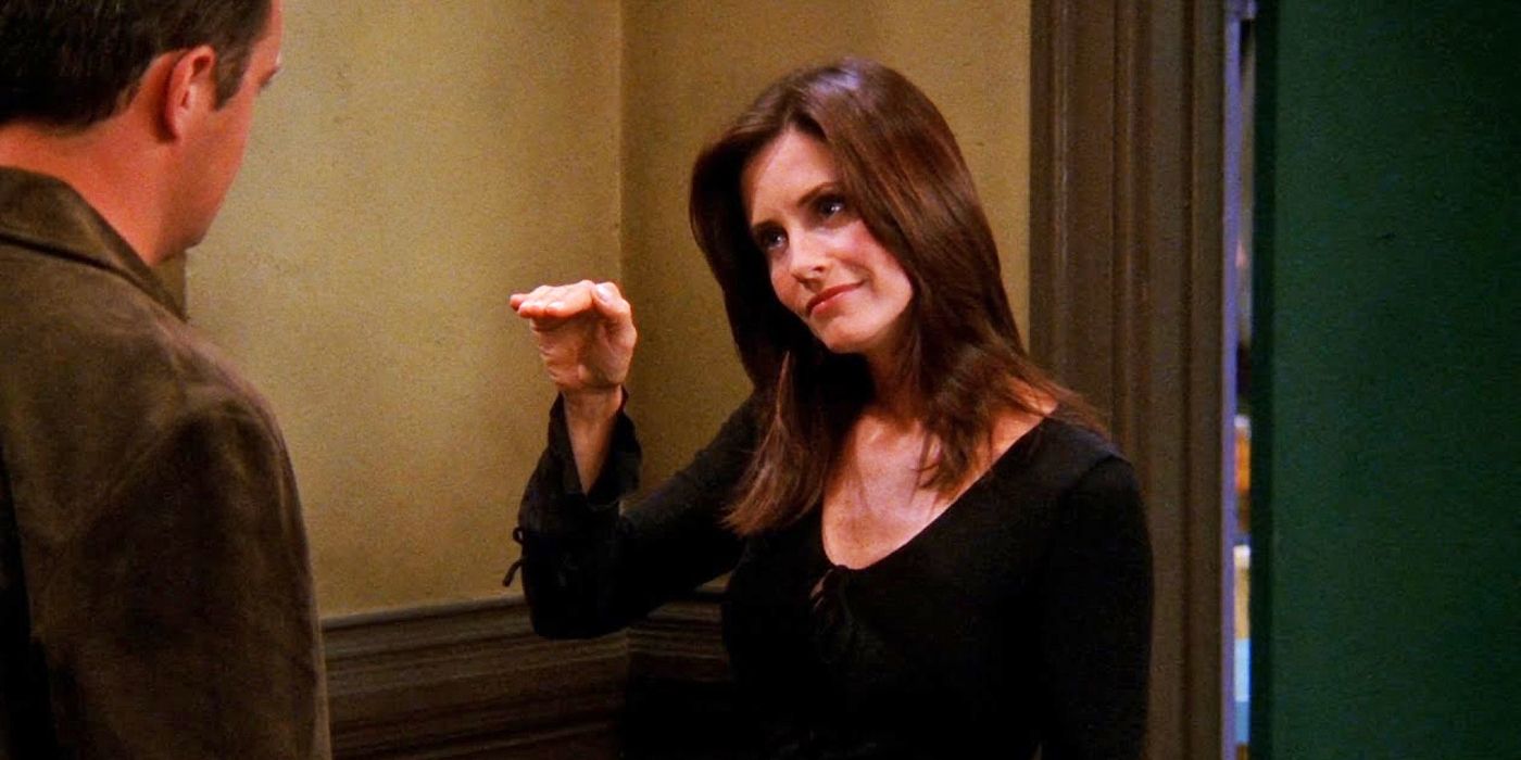 Courtney Cox as Monica in Friends with her hand up talking to Chandler in the hallway.